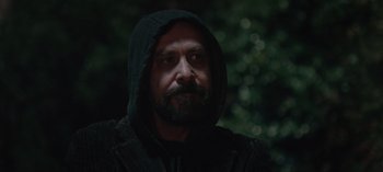 Movie still from “10 Days of a Good Man” (2023), directed by Uluç Bayraktar – A man with a beard wearing a hooded jacket; Close Up shot, Low angle