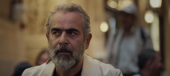 Movie still from “10 Days of a Good Man” (2023), directed by Uluç Bayraktar – An older man with a beard and a white coat; Close Up shot, Low angle