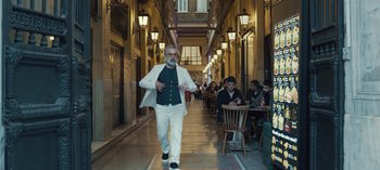 Movie still from “10 Days of a Good Man” (2023), directed by Uluç Bayraktar – A man walking down the street in a white suit; Wide shot, Low angle