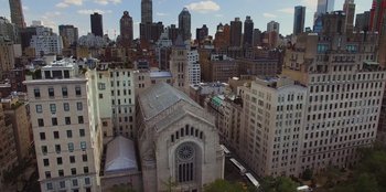 Movie still from “13: The Musical” (2022), directed by Tamra Davis – An aerial view of a city with a church and buildings; Extreme Wide shot, Overhead angle