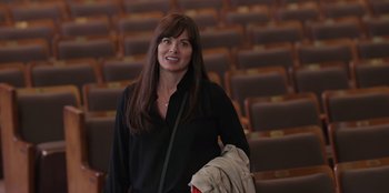 Movie still from “13: The Musical” (2022), directed by Tamra Davis – A woman in a black shirt is holding a backpack; Medium shot, High angle