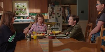 Movie still from “13: The Musical” (2022), directed by Tamra Davis – Two people sitting at a table with a bowl of cereal; Medium shot, Over the shoulder angle