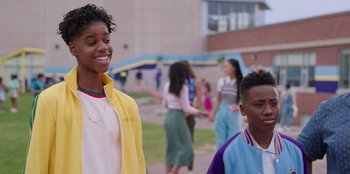 Movie still from “13: The Musical” (2022), directed by Tamra Davis – A couple of people standing next to each other on a field; Medium shot, Over the shoulder angle