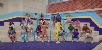 Movie still from “13: The Musical” (2022), directed by Tamra Davis – A group of people sitting on some steps; Wide shot, High angle