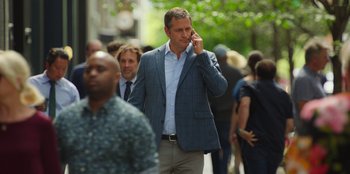 Movie still from “13: The Musical” (2022), directed by Tamra Davis – A man is talking on a cell phone on the street; Medium shot, Over the shoulder angle