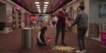 Movie still from “13: The Musical” (2022), directed by Tamra Davis – A man in a suit and tie standing on the floor; Wide shot, High angle