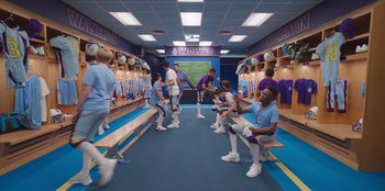 Movie still from “13: The Musical” (2022), directed by Tamra Davis – A group of young men sitting on benches in a locker room; Wide shot, High angle