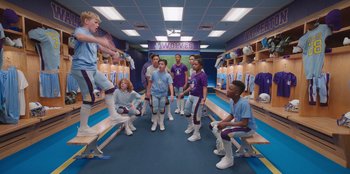 Movie still from “13: The Musical” (2022), directed by Tamra Davis – A group of young men standing around in a locker room; Wide shot, Over the shoulder angle