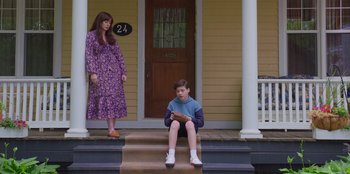 Movie still from “13: The Musical” (2022), directed by Tamra Davis – A woman and a boy sitting on the steps of a house; Wide shot, High angle