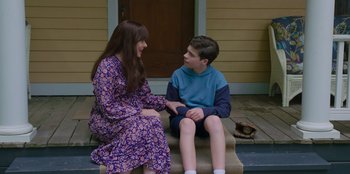 Movie still from “13: The Musical” (2022), directed by Tamra Davis – A young boy and a young girl sitting on a porch; Medium shot, Over the shoulder angle