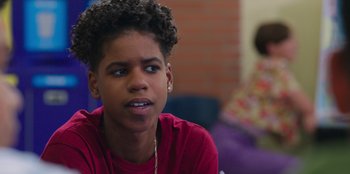 Movie still from “13: The Musical” (2022), directed by Tamra Davis – A young man with a red shirt is sitting in a room; Close Up shot, Over the shoulder angle