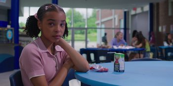 Movie still from “13: The Musical” (2022), directed by Tamra Davis – A young girl sitting at a table with a box of juice; Close Up shot, Over the shoulder angle