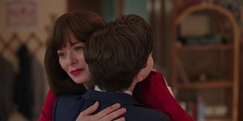 Movie still from “13: The Musical” (2022), directed by Tamra Davis – A woman is hugging a young boy in front of a wall; Close Up shot, Over the shoulder angle