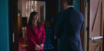 Movie still from “13: The Musical” (2022), directed by Tamra Davis – A woman in a red dress standing next to a man in a blue suit; Medium shot, Over the shoulder angle