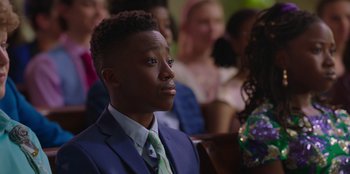 Movie still from “13: The Musical” (2022), directed by Tamra Davis – A man in a blue suit and a green neck tie; Close Up shot, Over the shoulder angle