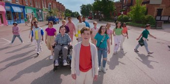Movie still from “13: The Musical” (2022), directed by Tamra Davis – A group of children are walking down the street; Wide shot, High angle