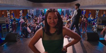 Movie still from “13: The Musical” (2022), directed by Tamra Davis – A young girl posing in front of an audience; Medium shot, Over the shoulder angle