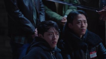 A man in a black jacket is looking into the distance