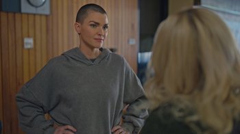 A woman with a shaved head standing in front of a mirror