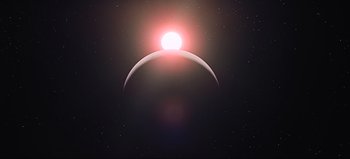Movie still from “2001: A Space Odyssey” (1968), directed by Stanley Kubrick – The sun is setting behind a crescent moon in the sky; Extreme Wide shot, Low angle