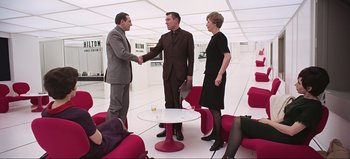 Movie still from “2001: A Space Odyssey” (1968), directed by Stanley Kubrick – Two men and a woman shaking hands in a room; Wide shot, Over the shoulder angle