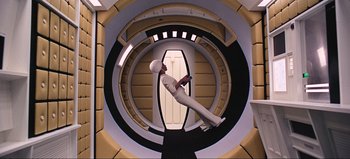 Movie still from “2001: A Space Odyssey” (1968), directed by Stanley Kubrick – A man in a white suit is standing in a circular staircase; Wide shot, Overhead angle