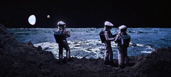 Movie still from “2001: A Space Odyssey” (1968), directed by Stanley Kubrick – A group of people in spacesuits standing on the side of the moon; Extreme Wide shot, Overhead angle