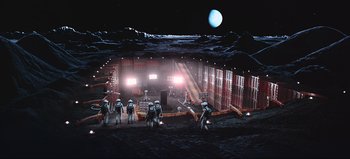 Movie still from “2001: A Space Odyssey” (1968), directed by Stanley Kubrick – A group of people standing on top of a dirt field; Extreme Wide shot, High angle