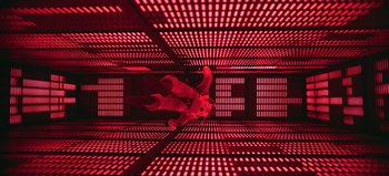 Movie still from “2001: A Space Odyssey” (1968), directed by Stanley Kubrick – A person standing in a room with red lights; Extreme Wide shot, Overhead angle