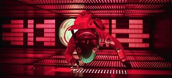 A man in a red suit is standing in front of a computer screen
