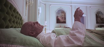 Movie still from “2001: A Space Odyssey” (1968), directed by Stanley Kubrick – A man laying on a bed in a room with a painting on the wall behind him; Medium shot, Overhead angle