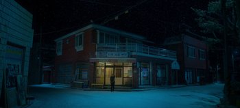 Movie still from “20th Century Girl” (2022), directed by Woo-ri Bang – A person standing in front of a building at night; Extreme Wide shot, Low angle