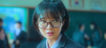 Movie still from “20th Century Girl” (2022), directed by Woo-ri Bang – A woman wearing glasses and a suit jacket; Close Up shot, Over the shoulder angle