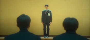 Movie still from “20th Century Girl” (2022), directed by Woo-ri Bang – A man standing in front of a yellow wall; Wide shot, Low angle