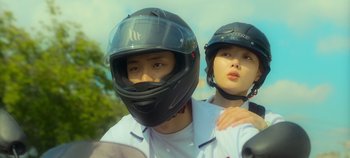 Movie still from “20th Century Girl” (2022), directed by Woo-ri Bang – A man and a woman wearing a helmet and riding a motorcycle; Close Up shot, Low angle