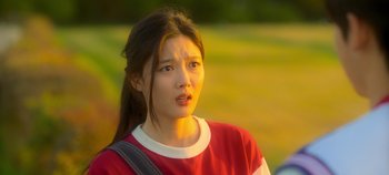 Movie still from “20th Century Girl” (2022), directed by Woo-ri Bang – A young woman in a red and white t - shirt looks to her left; Close Up shot, Over the shoulder angle