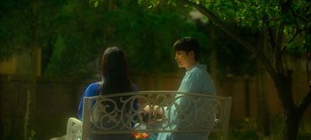 Movie still from “20th Century Girl” (2022), directed by Woo-ri Bang – A man and a woman are sitting on a bench; Medium shot, Over the shoulder angle