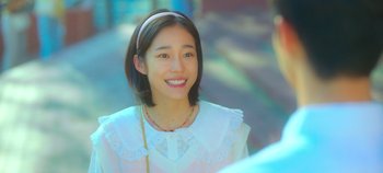 Movie still from “20th Century Girl” (2022), directed by Woo-ri Bang – A young woman smiles brightly as she walks down the street; Close Up shot, Over the shoulder angle