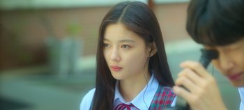 Movie still from “20th Century Girl” (2022), directed by Woo-ri Bang – A young woman with long black hair wearing a red and white tie; Close Up shot, Over the shoulder angle