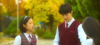 Movie still from “20th Century Girl” (2022), directed by Woo-ri Bang – A young man and a young woman standing next to each other; Medium shot, Low angle
