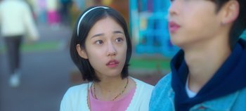 Movie still from “20th Century Girl” (2022), directed by Woo-ri Bang – A young woman with short black hair wearing a pink shirt; Close Up shot, Over the shoulder angle