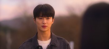 Movie still from “20th Century Girl” (2022), directed by Woo-ri Bang – A young man with black hair wearing a jean jacket; Close Up shot, Over the shoulder angle