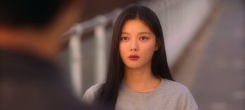 Movie still from “20th Century Girl” (2022), directed by Woo-ri Bang – A woman with long black hair wearing a gray shirt; Close Up shot, Over the shoulder angle