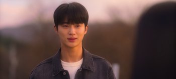 Movie still from “20th Century Girl” (2022), directed by Woo-ri Bang – A young man with black hair wearing a jean jacket; Close Up shot, Over the shoulder angle