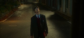 Movie still from “20th Century Girl” (2022), directed by Woo-ri Bang – A man in a suit and tie standing on a street; Close Up shot, Low angle