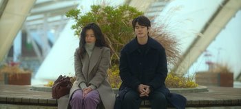 Movie still from “20th Century Girl” (2022), directed by Woo-ri Bang – A man and a woman sitting next to each other on a bench; Medium shot, High angle