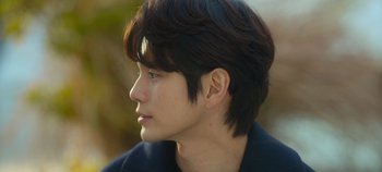 Movie still from “20th Century Girl” (2022), directed by Woo-ri Bang – A young man with long black hair looking to his left; Close Up shot, Over the shoulder angle