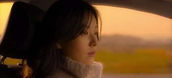 Movie still from “20th Century Girl” (2022), directed by Woo-ri Bang – A woman sitting in a car looking out the window; Close Up shot, Low angle