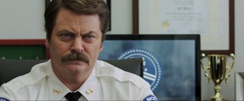 Movie still from “22 Jump Street” (2014), directed by Phil Lord – A man with a mustache sitting at a desk; Close Up shot, Over the shoulder angle