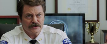 Movie still from “22 Jump Street” (2014), directed by Phil Lord – A man with a mustache sitting at a desk; Close Up shot, Over the shoulder angle